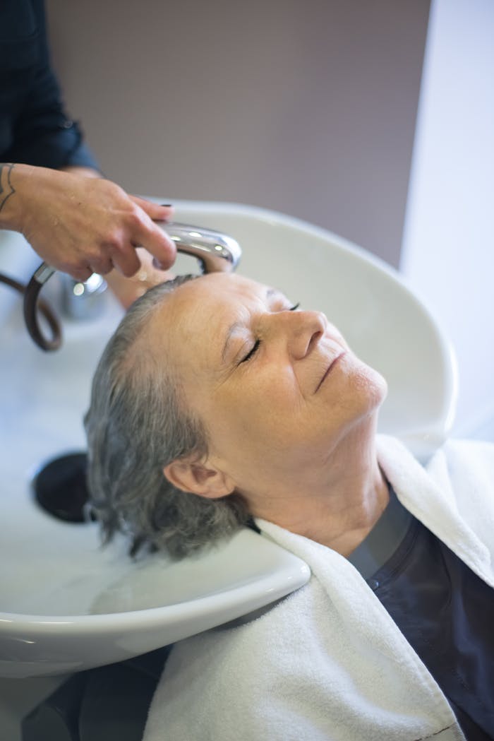 Senior woman enjoying a rejuvenating hair wash at a salon, showcasing relaxation and personal care.