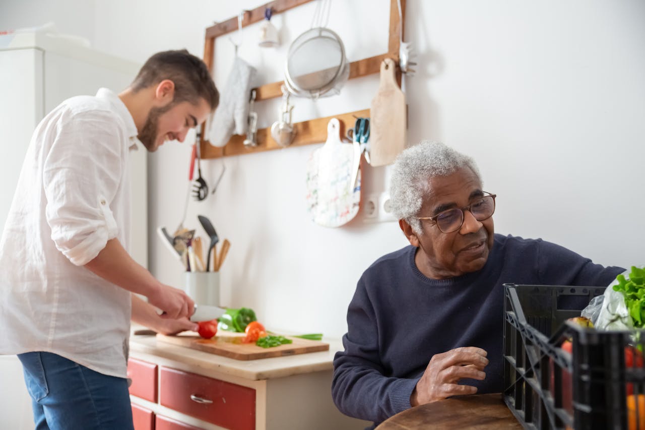A senior man and young man preparing vegetables together in a cozy kitchen setting.