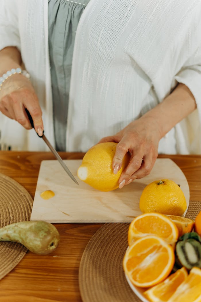A woman cutting lemons in the kitchen, preparing fresh juice.